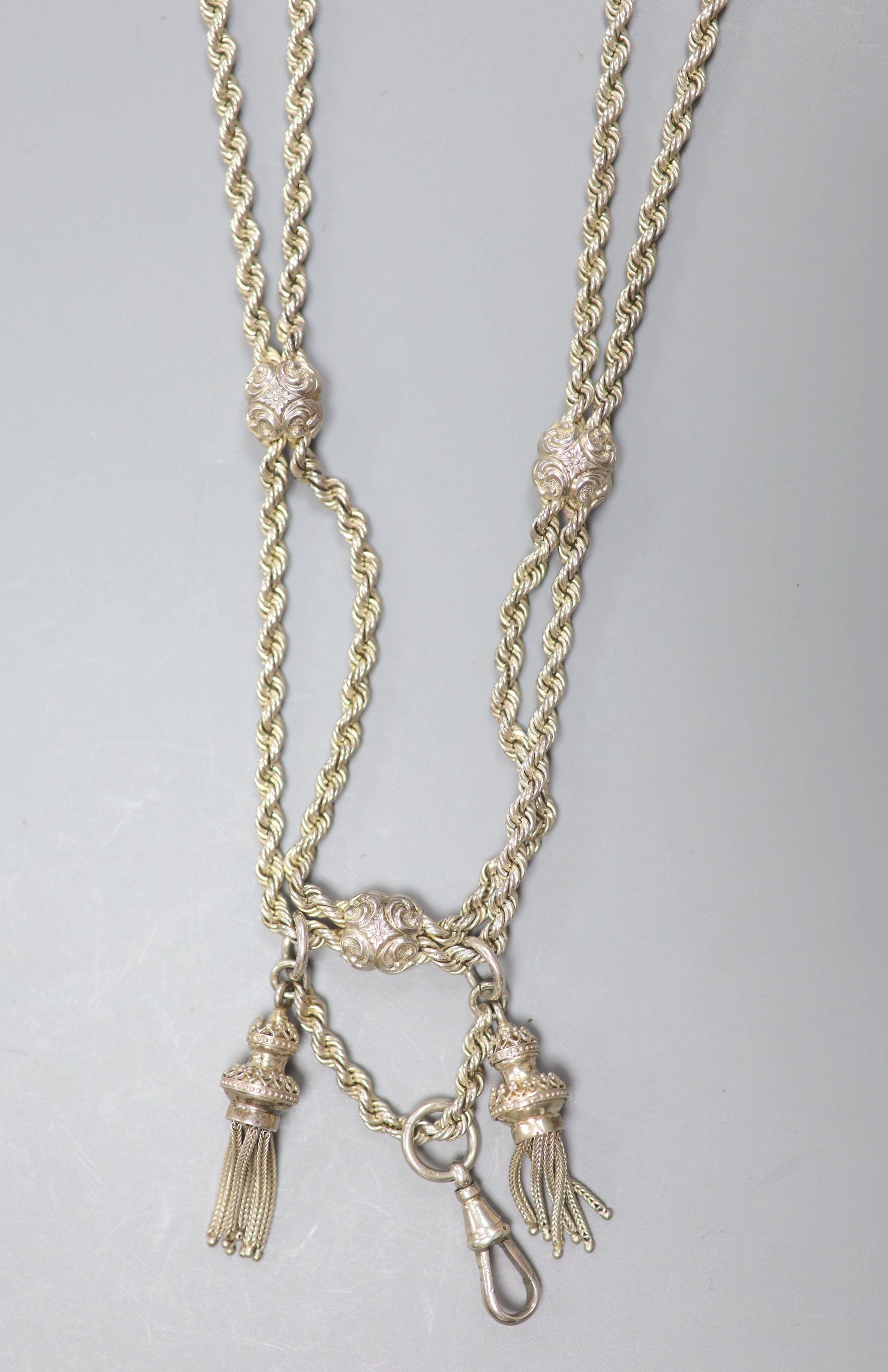 An Edwardian long silver ropetwist chain and openwork panel tassel necklace, with mask decoration